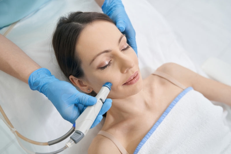 Woman receiving hydrafacial treatment with a hydrafacial machine in beauty salon